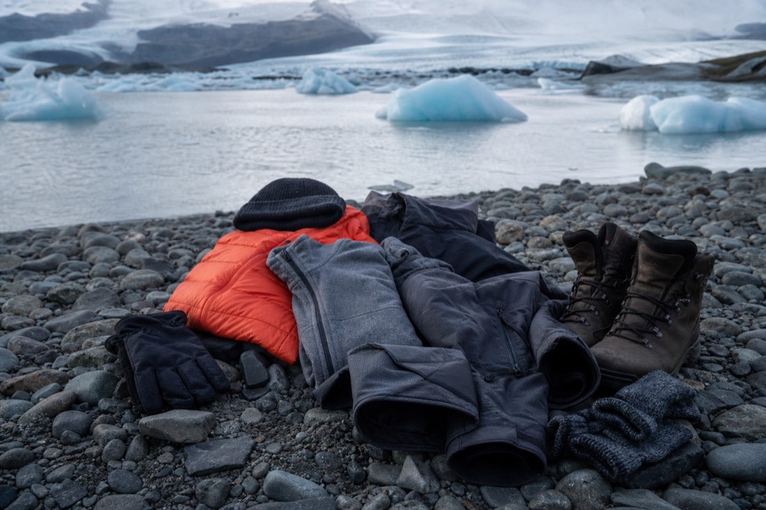 Warm windproof layers, hat, gloves and grippy boots laid out for a long winter day trip to Jökulsárlón and Diamond Beach