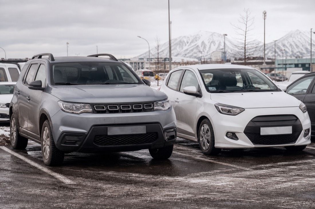A compact 4x4 SUV parked beside a small economy hatchback at a Reykjavik rental lot in winter, illustrating car choice for the Jokulsarlon drive